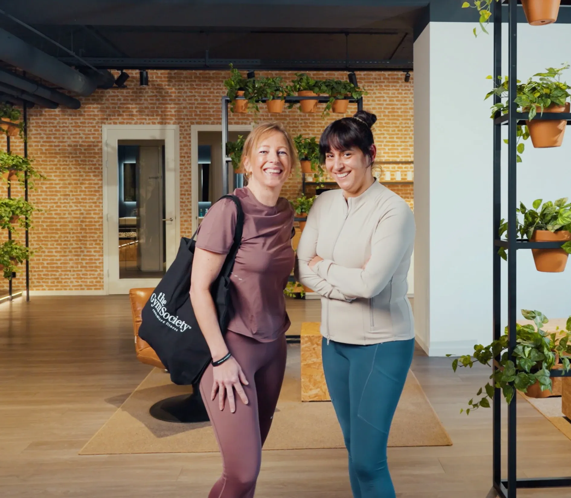 Twee leden staan ontspannen in lounge van The Gym Society na training