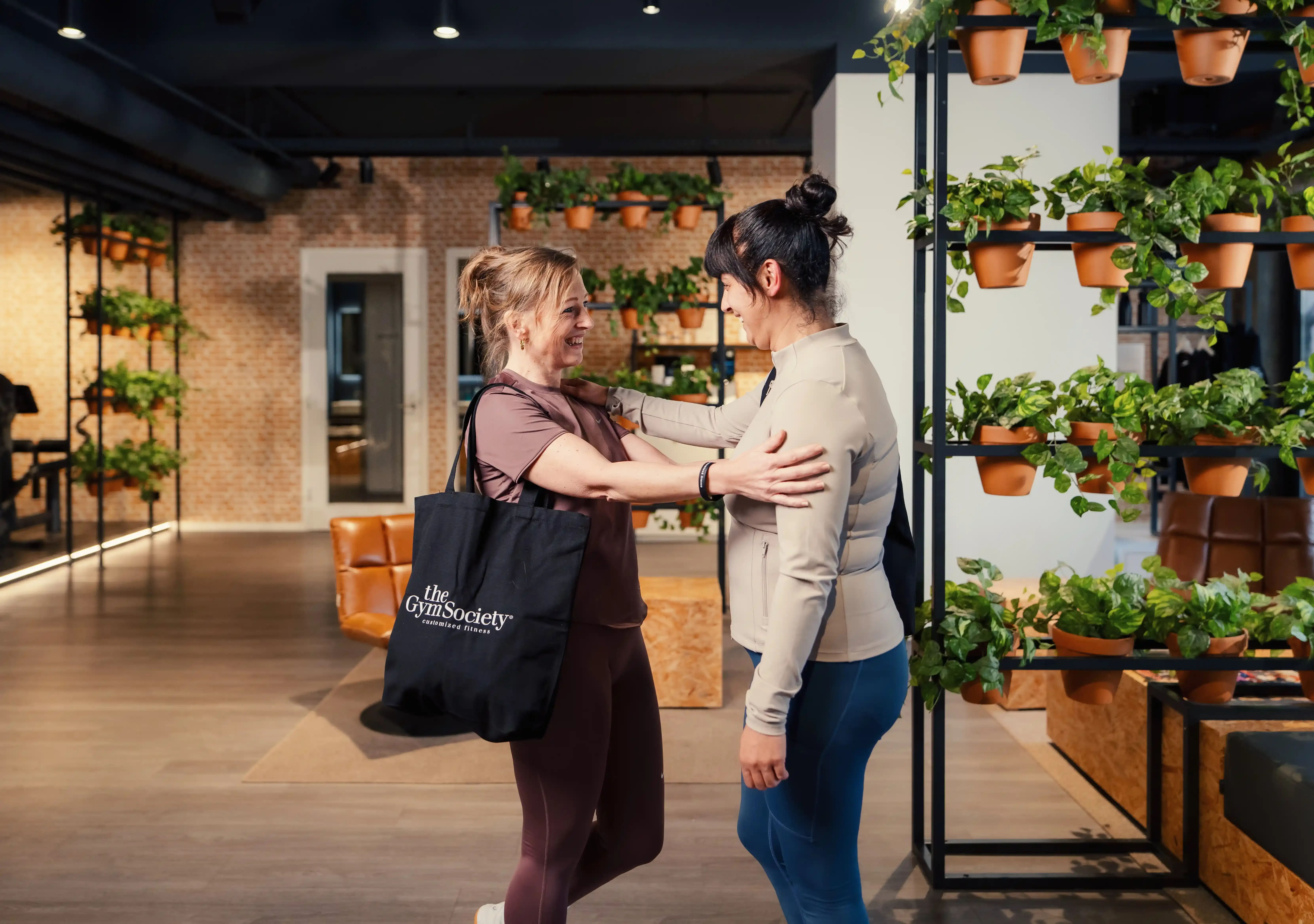 Twee leden begroeten elkaar in de lounge van The Gym Society