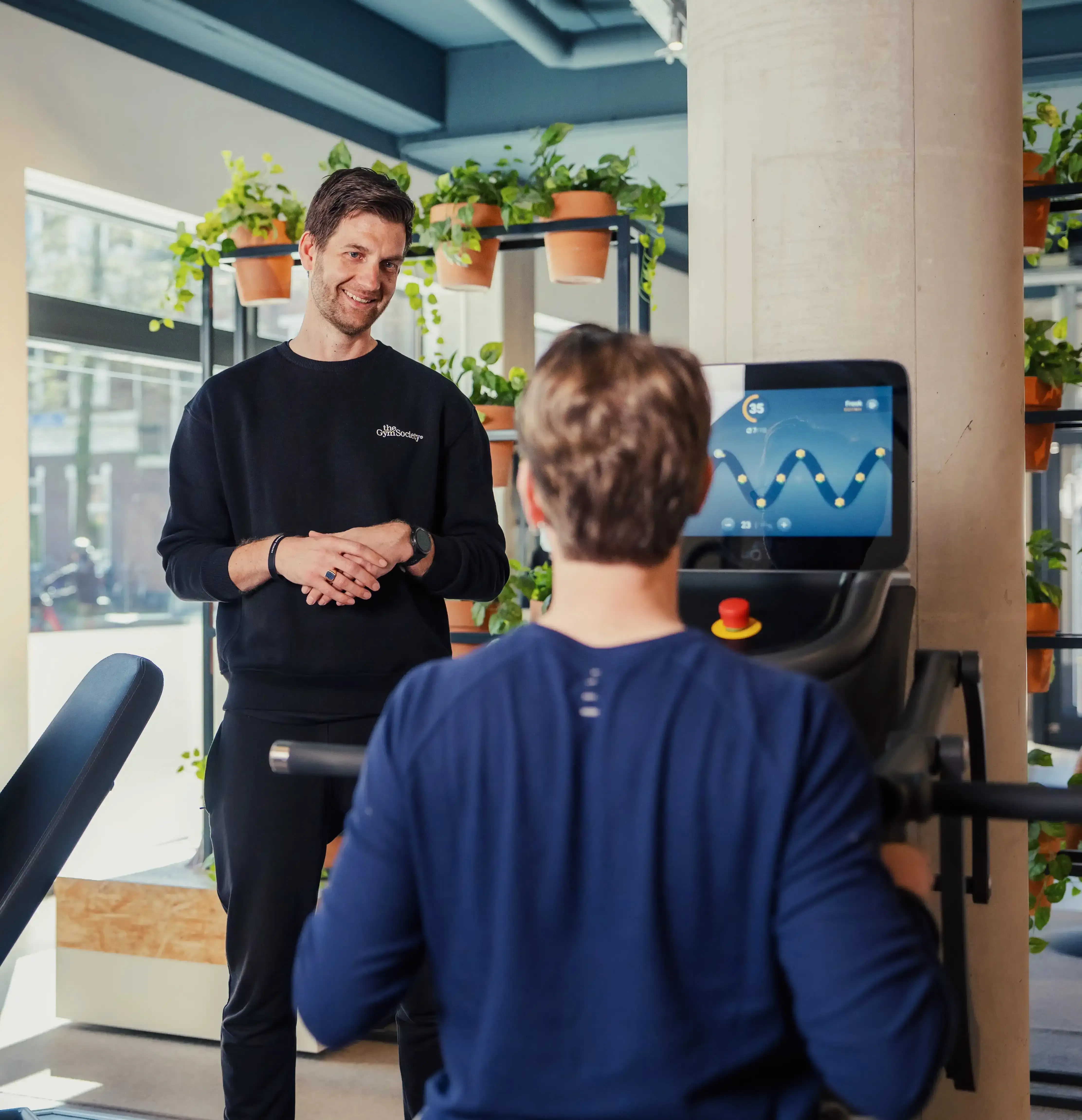 Coach begeleidt lid tijdens training op krachttoestel in The Gym Society