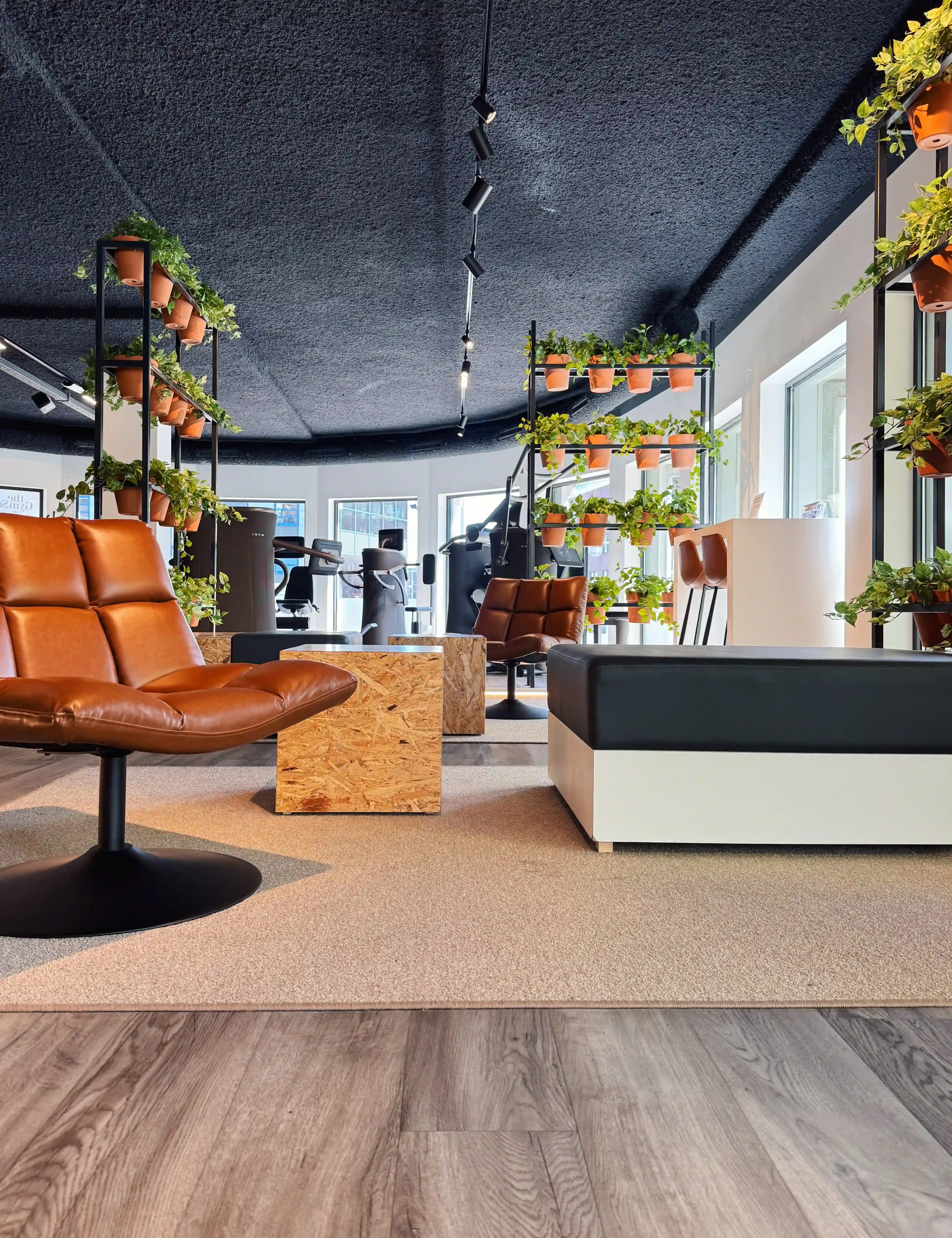 Overzicht van de lounge met zitplekken, planten en zicht op de trainingsruimte