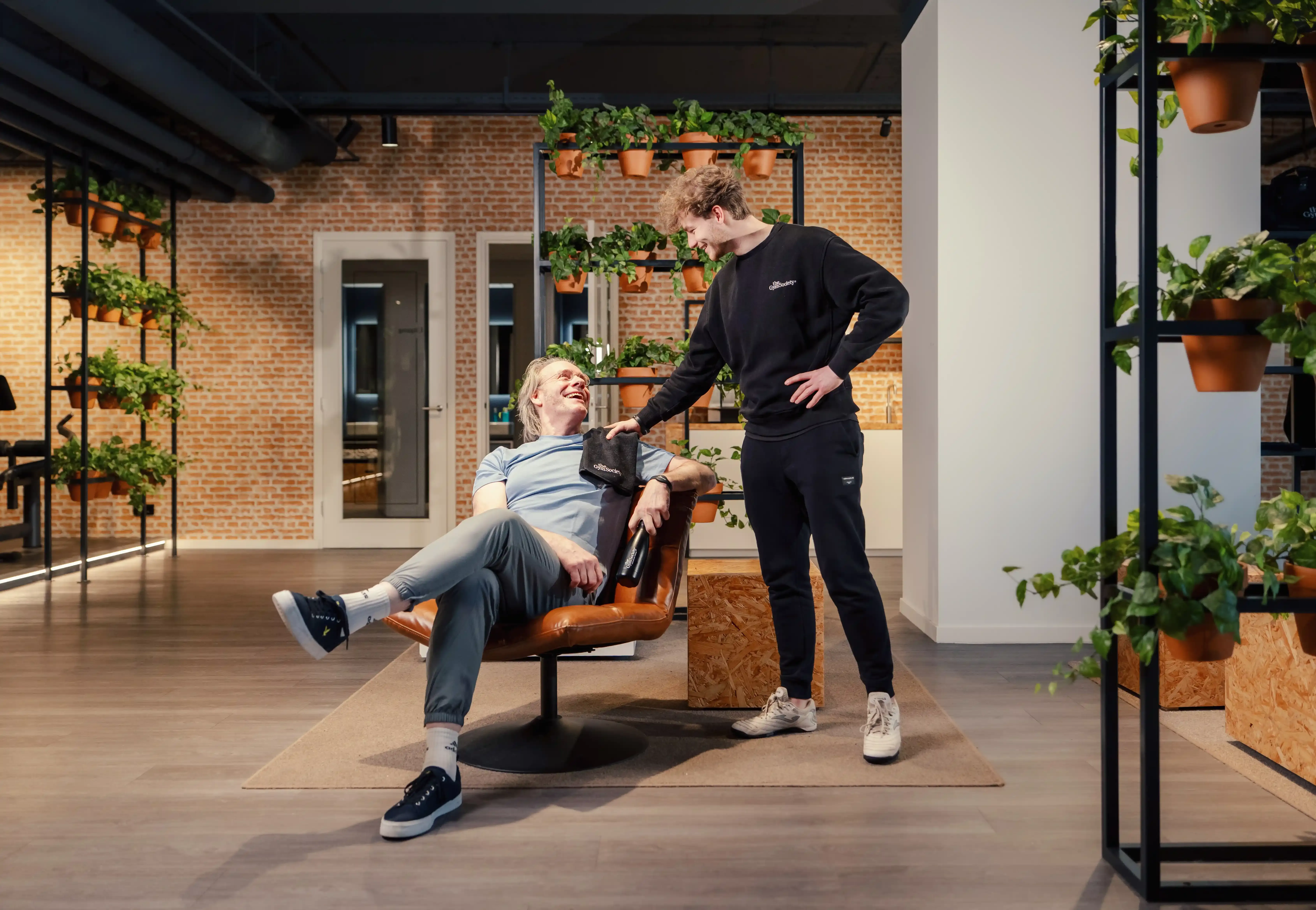 Coach maakt een praatje met een lid in de lounge