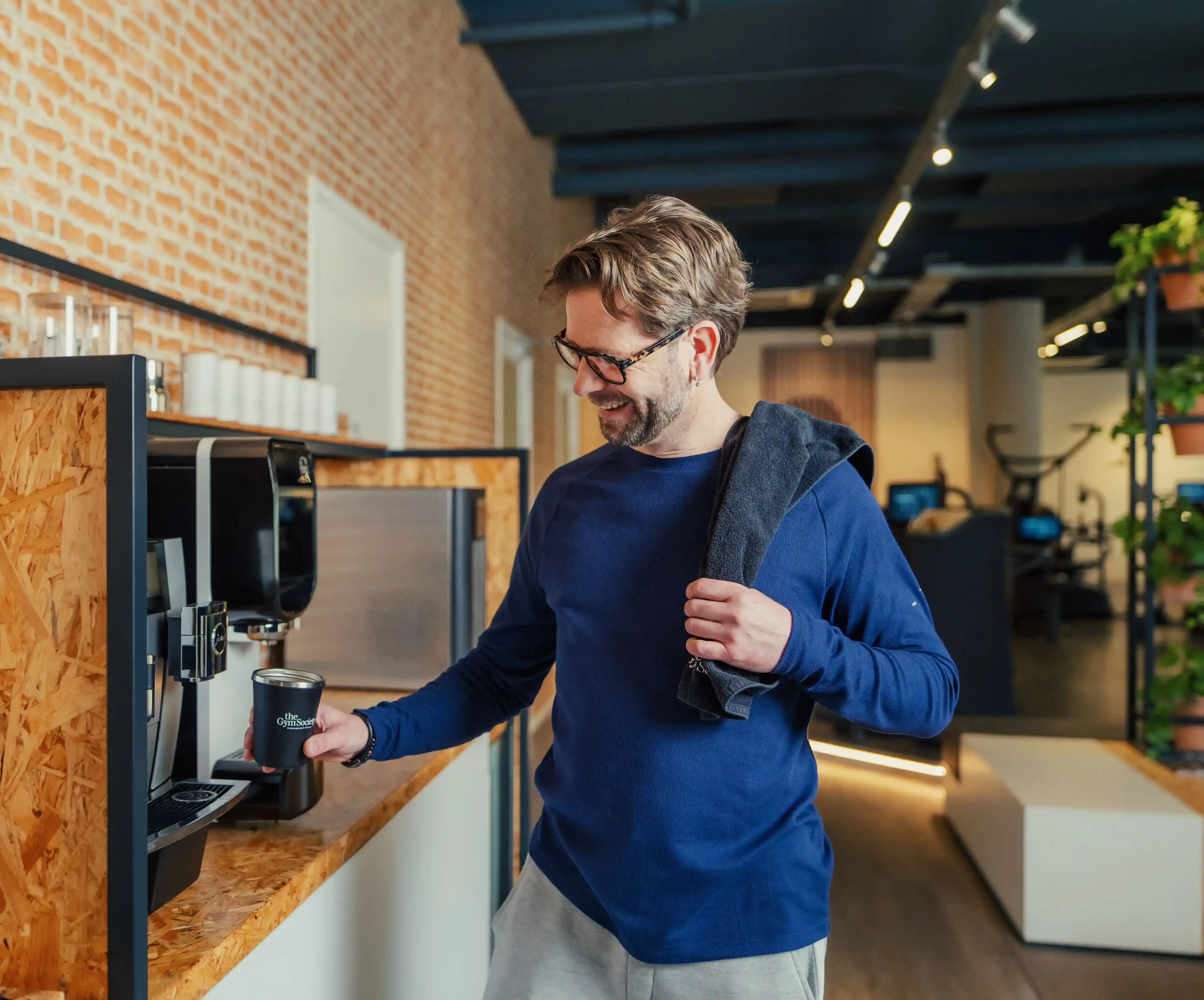 Lid pakt koffie na training in lounge van The Gym Society