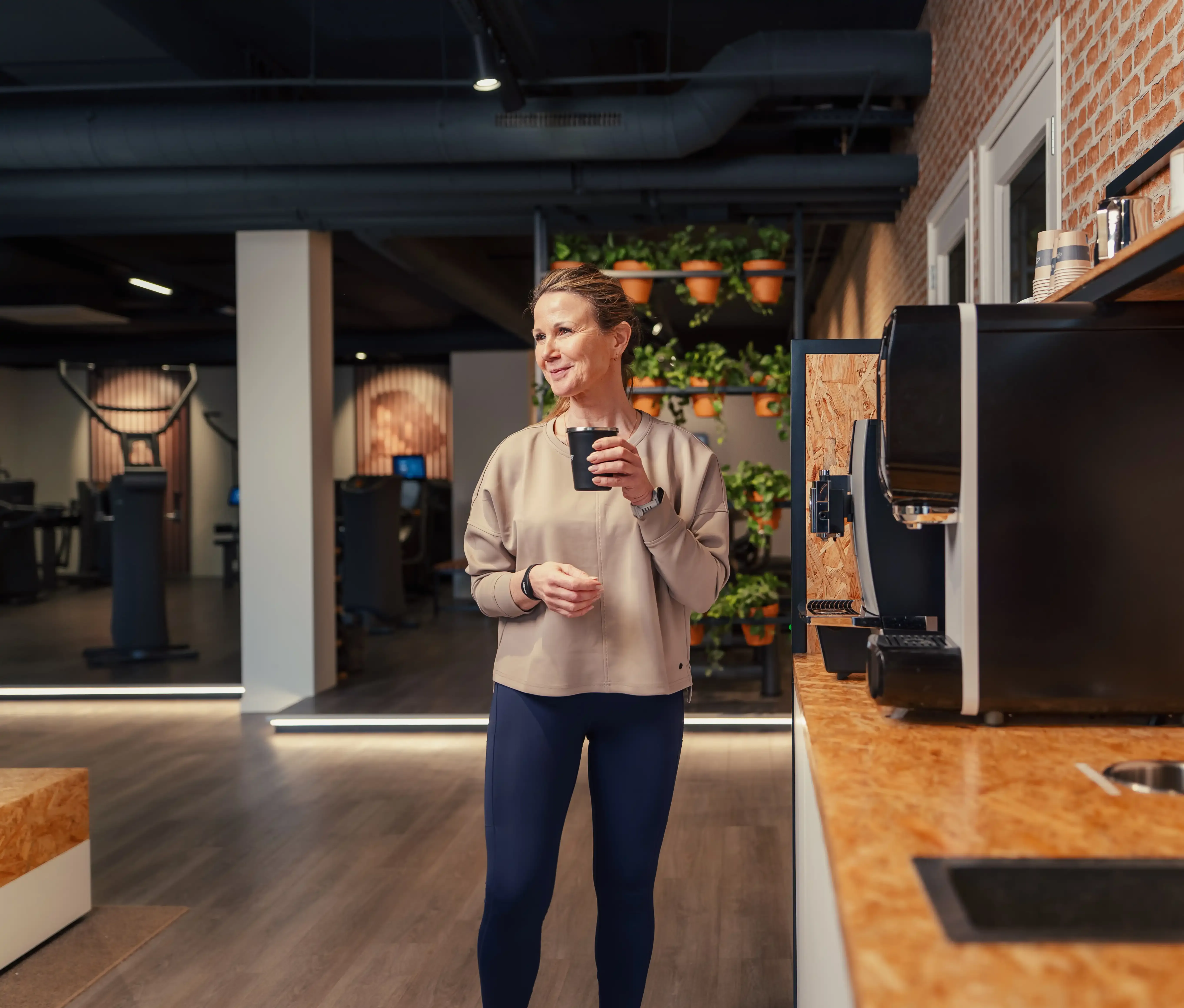 Lid staat met koffie in de lounge en kijkt ontspannen de ruimte in