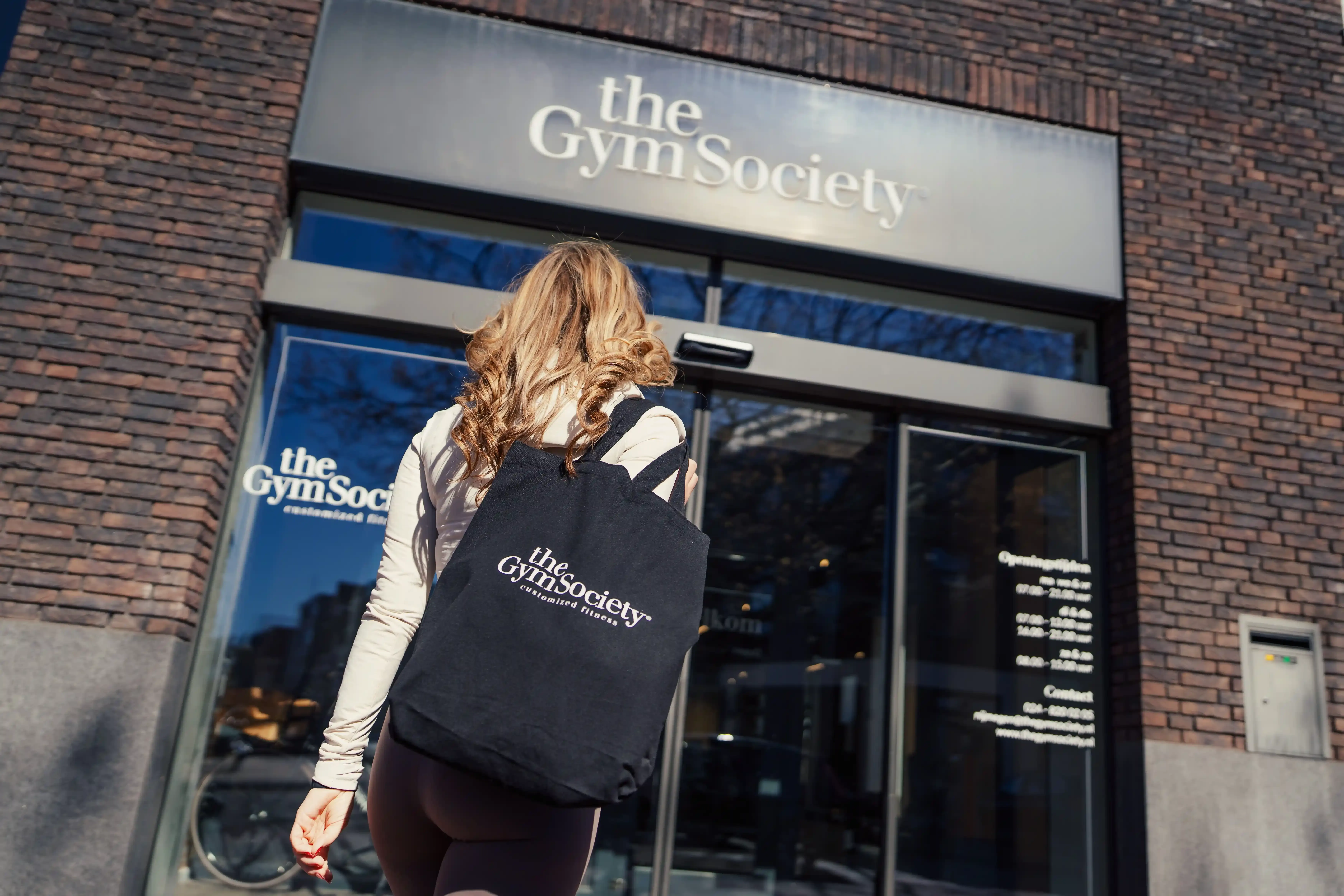Lid komt de studio binnen met The Gym Society tas en gevel zichtbaar