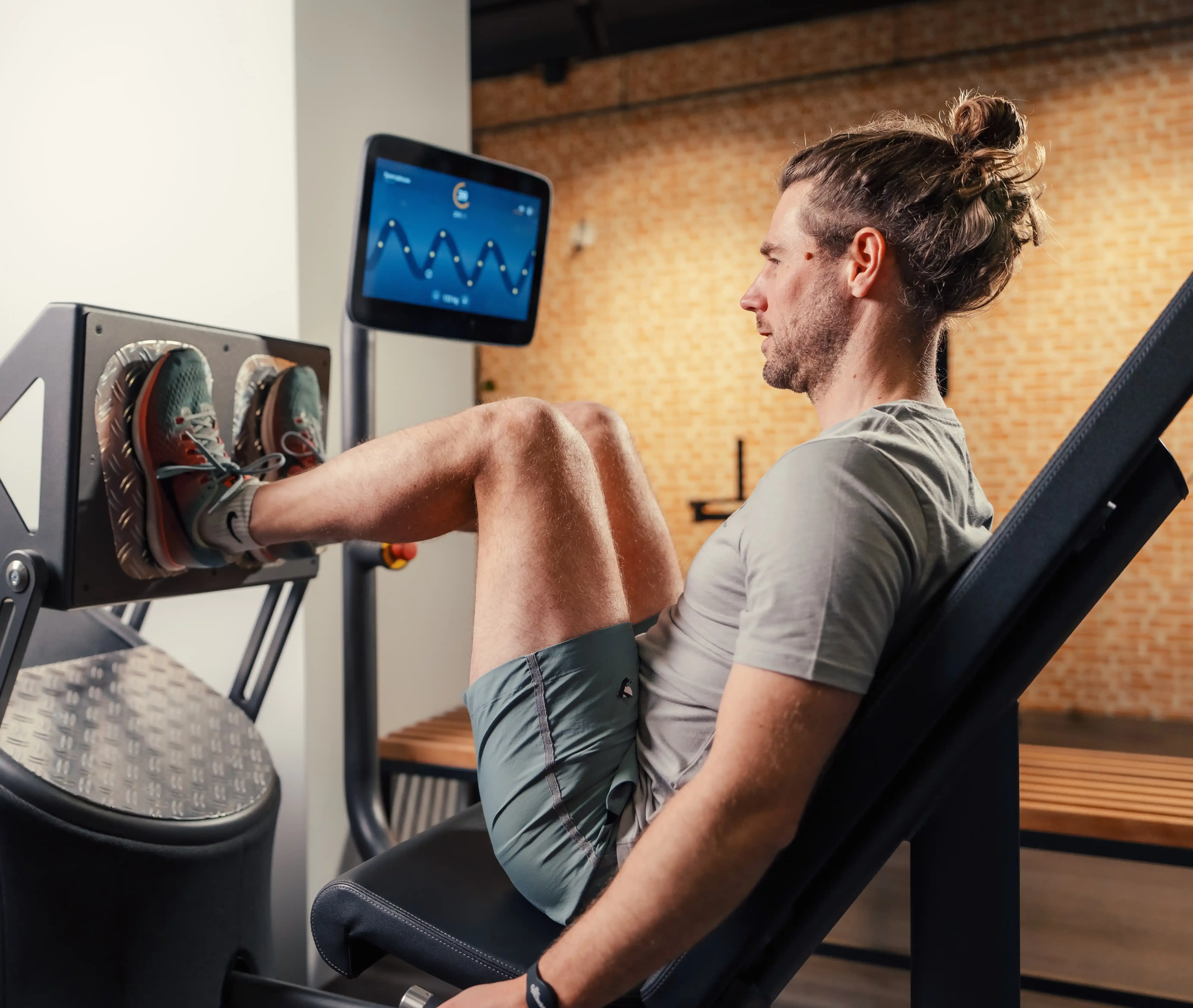 Actiebeeld van Leg Press training met scherm op de achtergrond