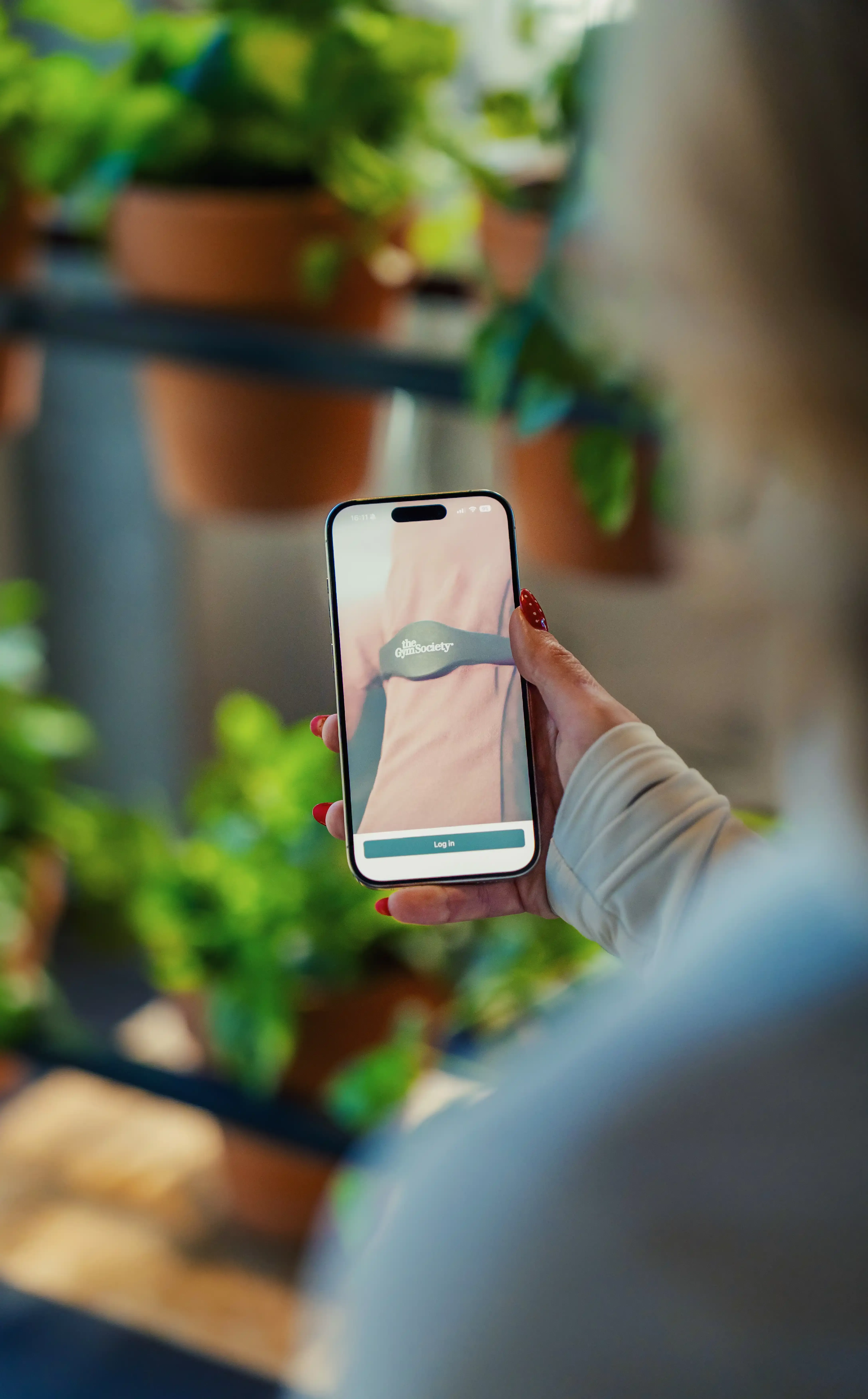 Lid houdt telefoon vast met het inlogscherm van de app zichtbaar