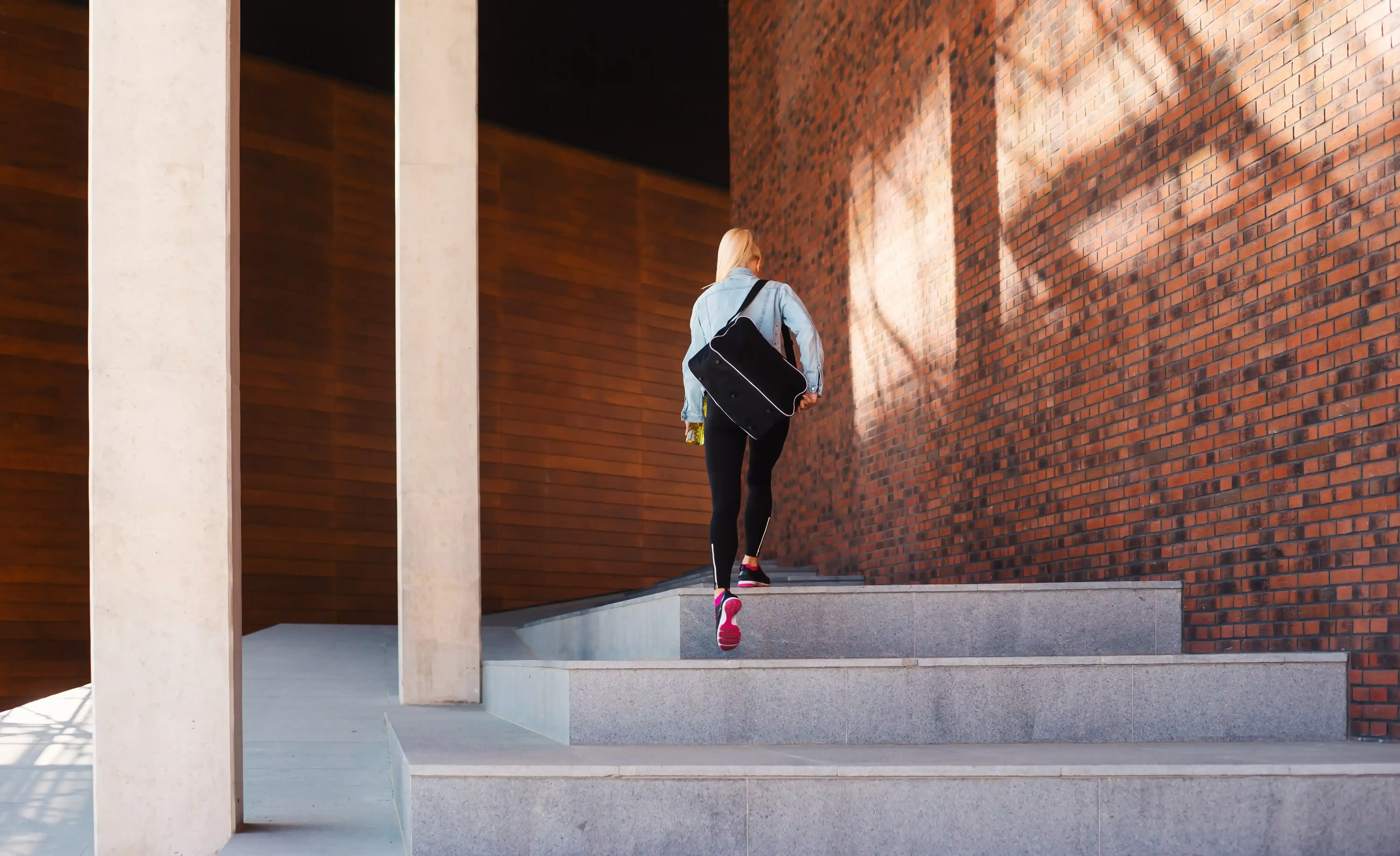 Vrouw loopt met sporttas richting haar workout