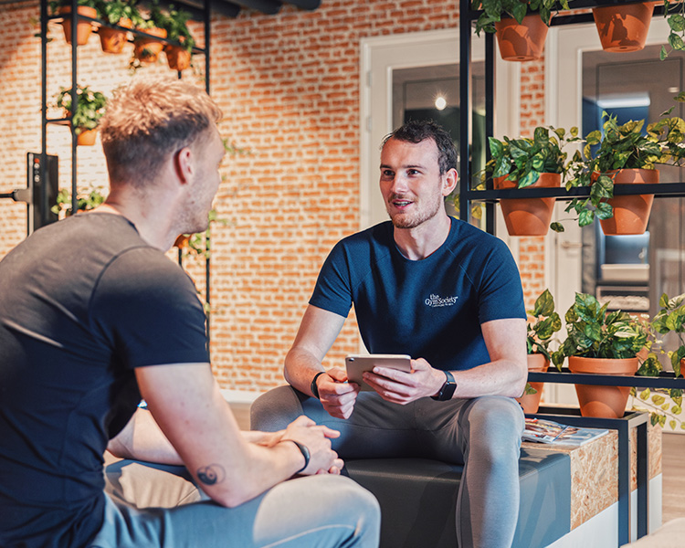 Een lid en coach van The Gym Society die samen in de lounge een Lifestyle Plan aan het samenstellen zijn