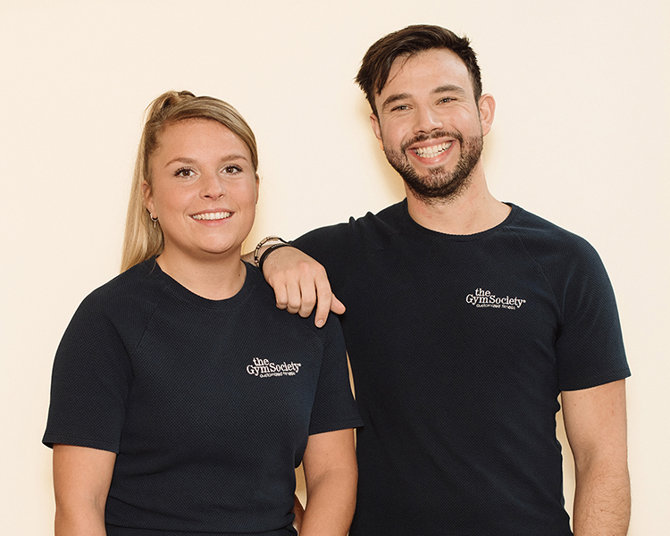 Twee Lifestyle Coaches van The Gym Society die arm in arm voor de camera poseren