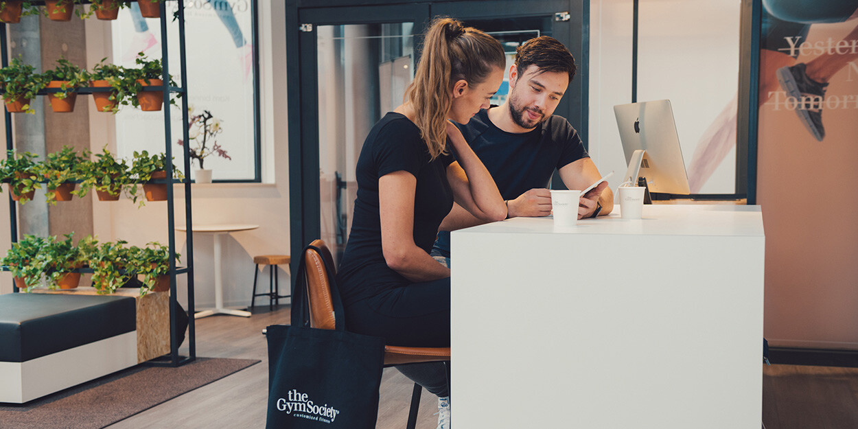 Een Lifestyle Coach en lid van The Gym Society die samen in de lounge het onboarding traject aan het doorspreken zijn