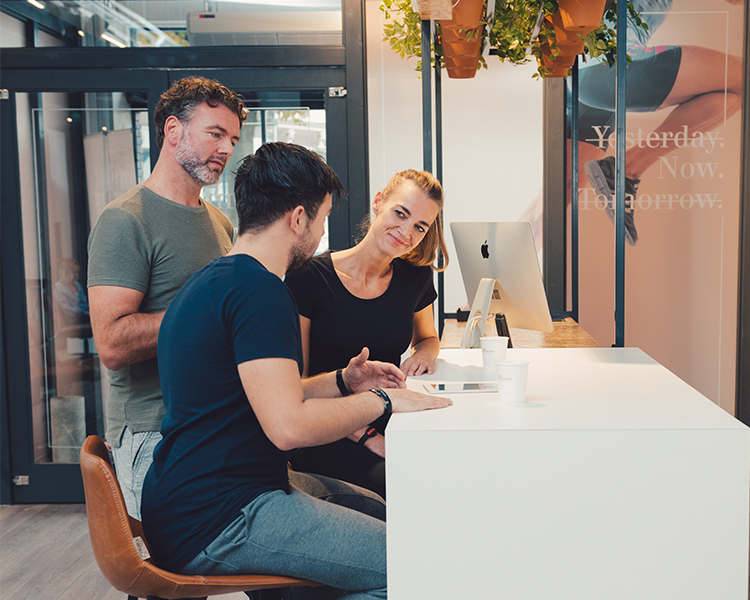 Twee leden die met een Lifestyle Coach van The Gym Society in gesprek zijn